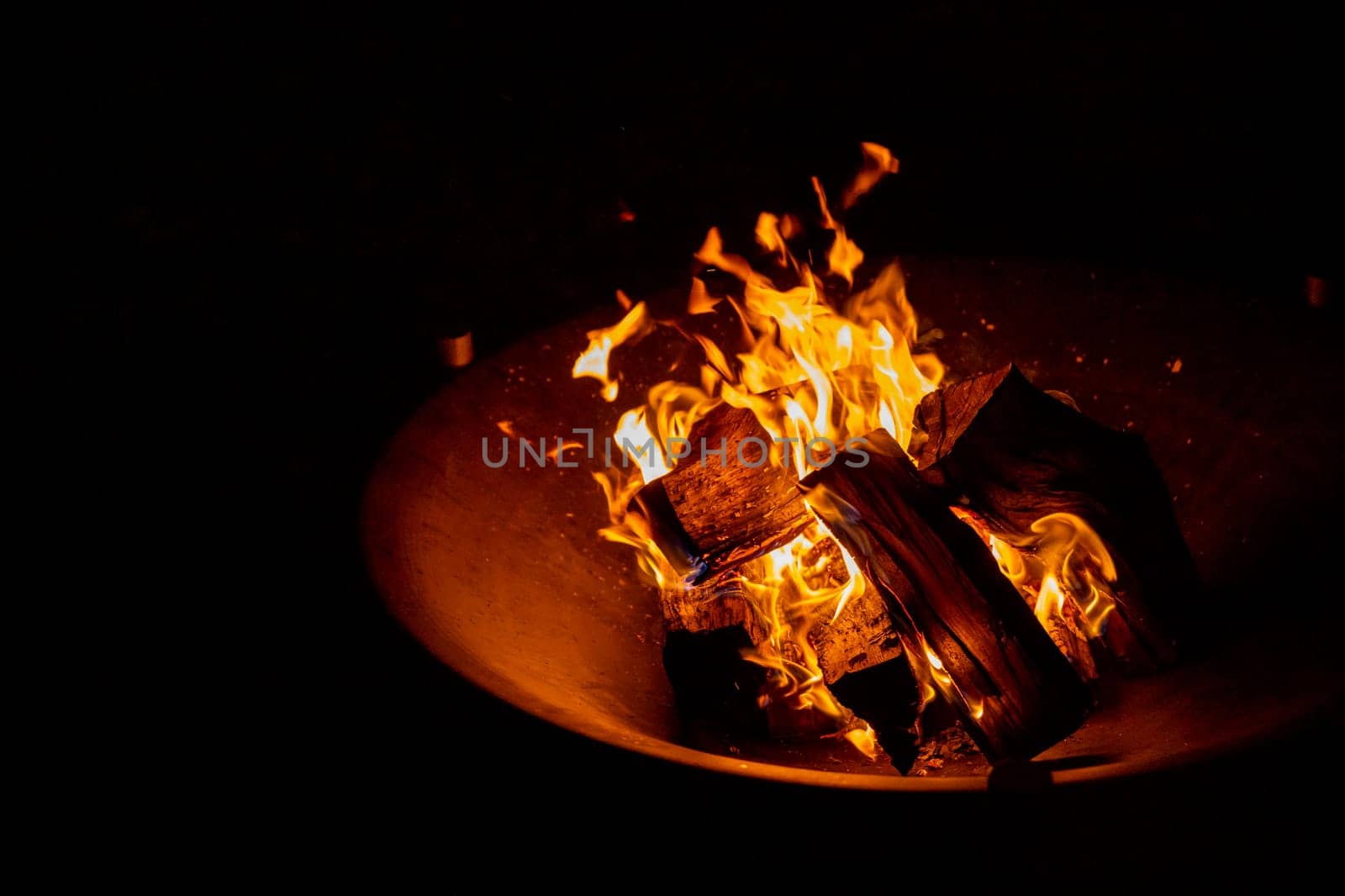 big bonfire in an old rusty fire bowl used for decoration a party.