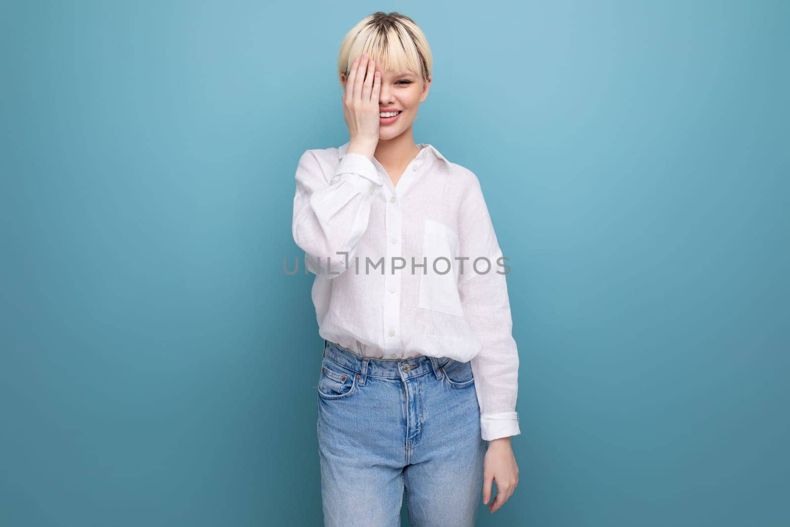 portrait of a young pretty blond secretary woman dressed in a white blouse on a blue background with copy space.