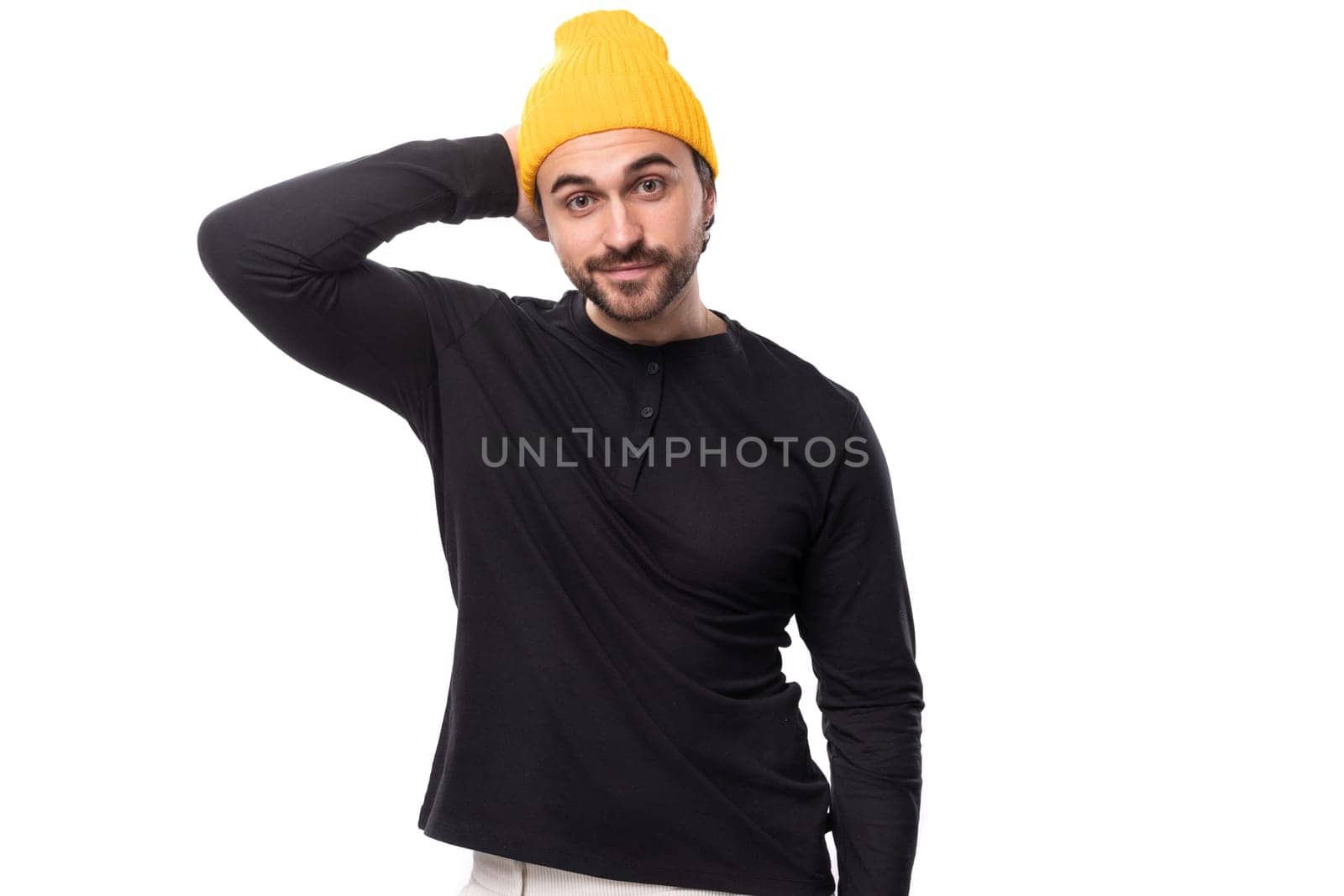 successful 30s authentic brunet male adult in black sweater and yellow cap on white background with copy space.