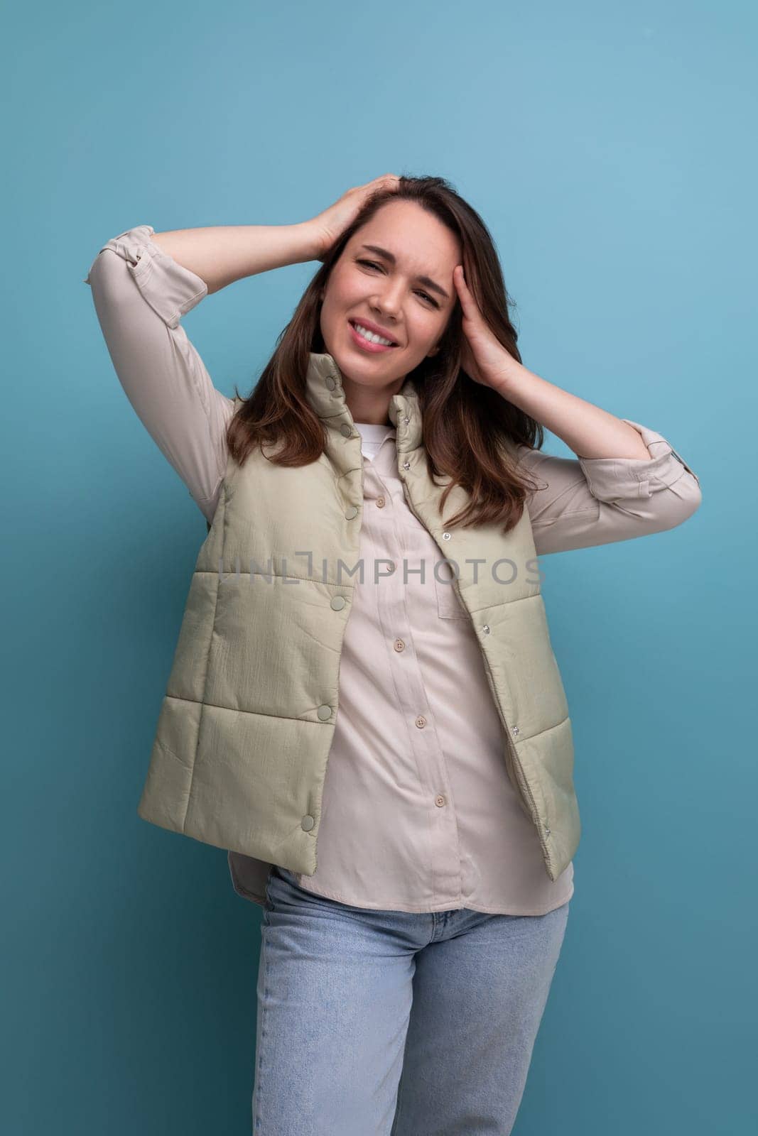 brunette young woman holding her head and posing on studio background.