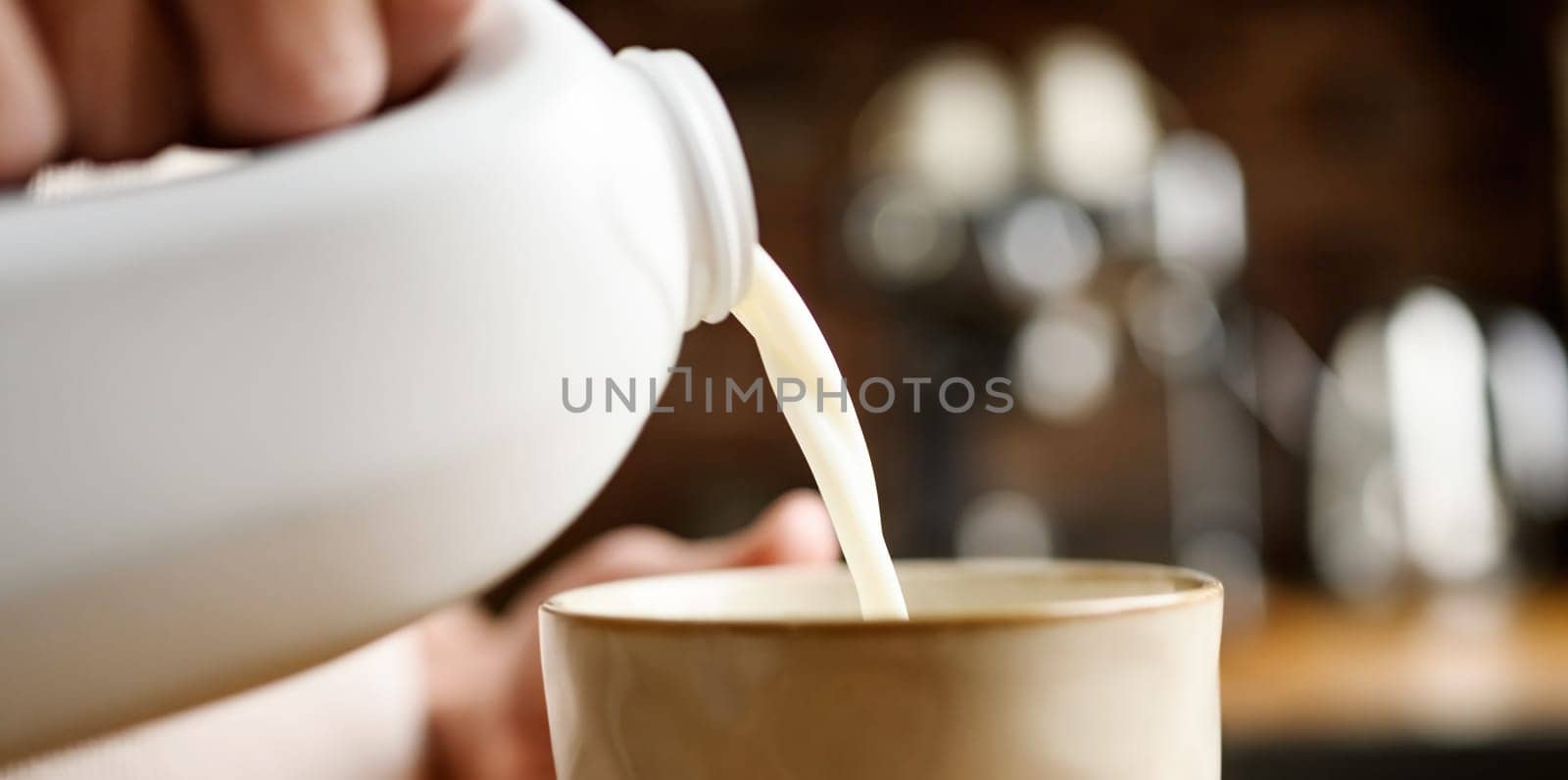 Girl with pouring milk in cup at kitchen at home
