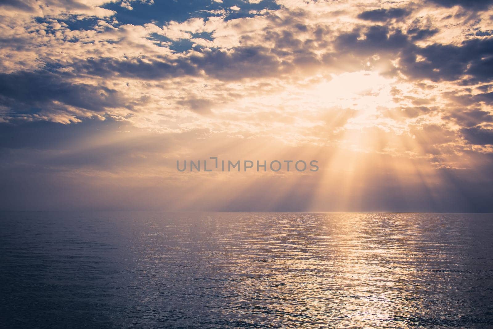 Beautiful sunset over the sea.
Sunbeams are shining through the clouds.