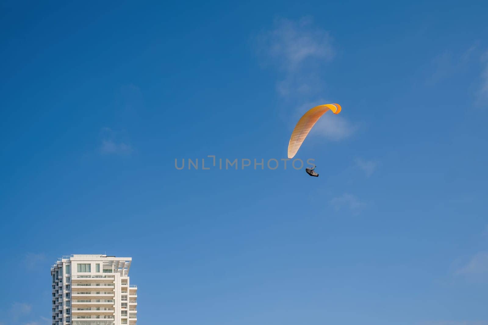 paragliding. extreme sport. Paraglider silhouette flying in the blue sky over the city. by Renisons