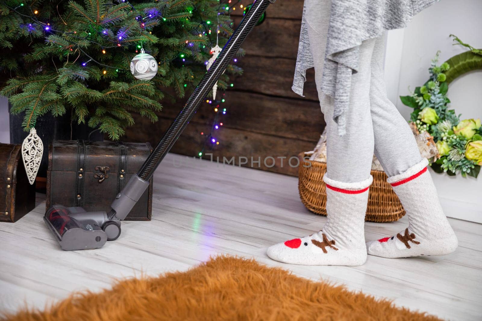 Before Christmas, thorough preparations and cleaning around the house are taking place. Vacuuming under the Christmas tree.