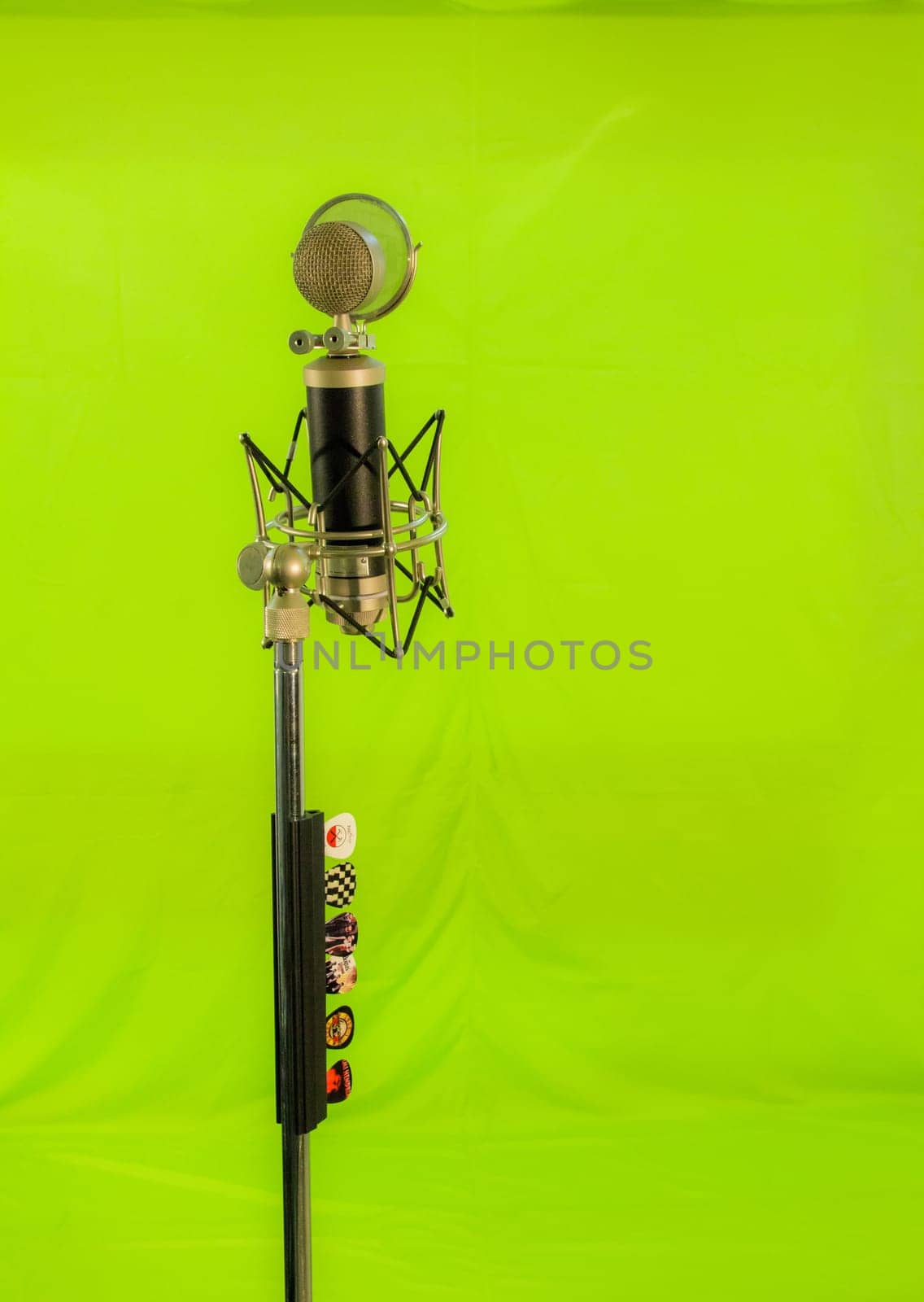 Vocal condenser microphone with wind screen isolated on green background.