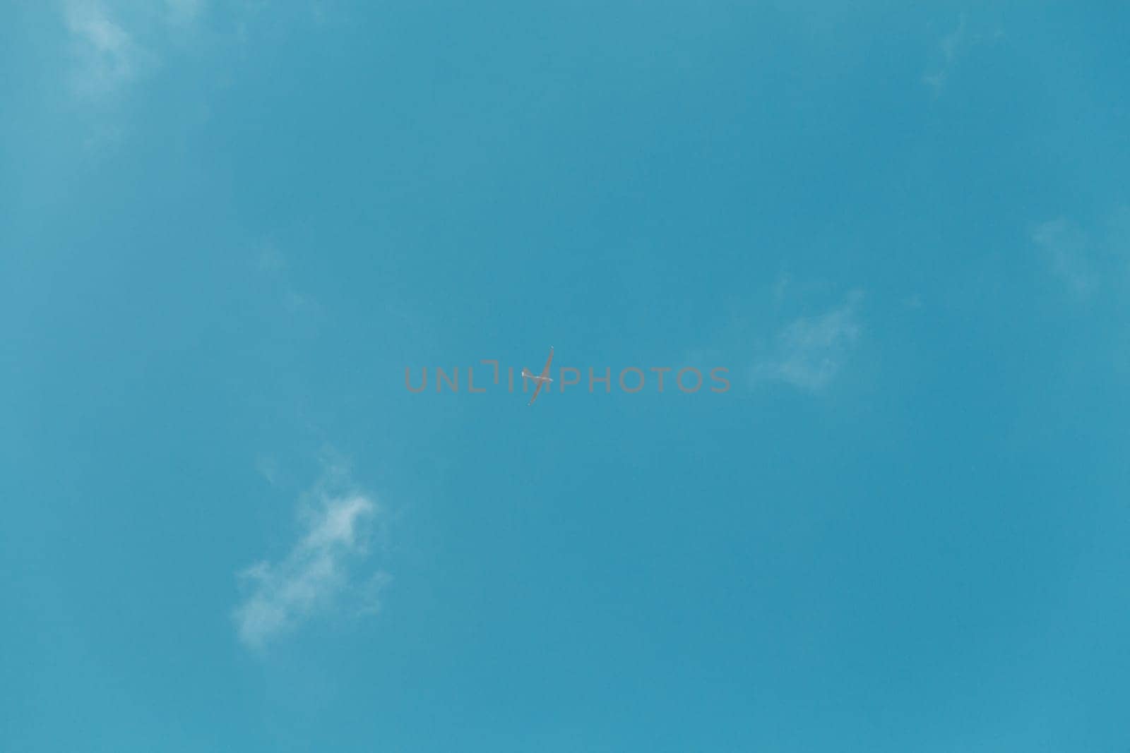 Glider gliding in blue sky from below.