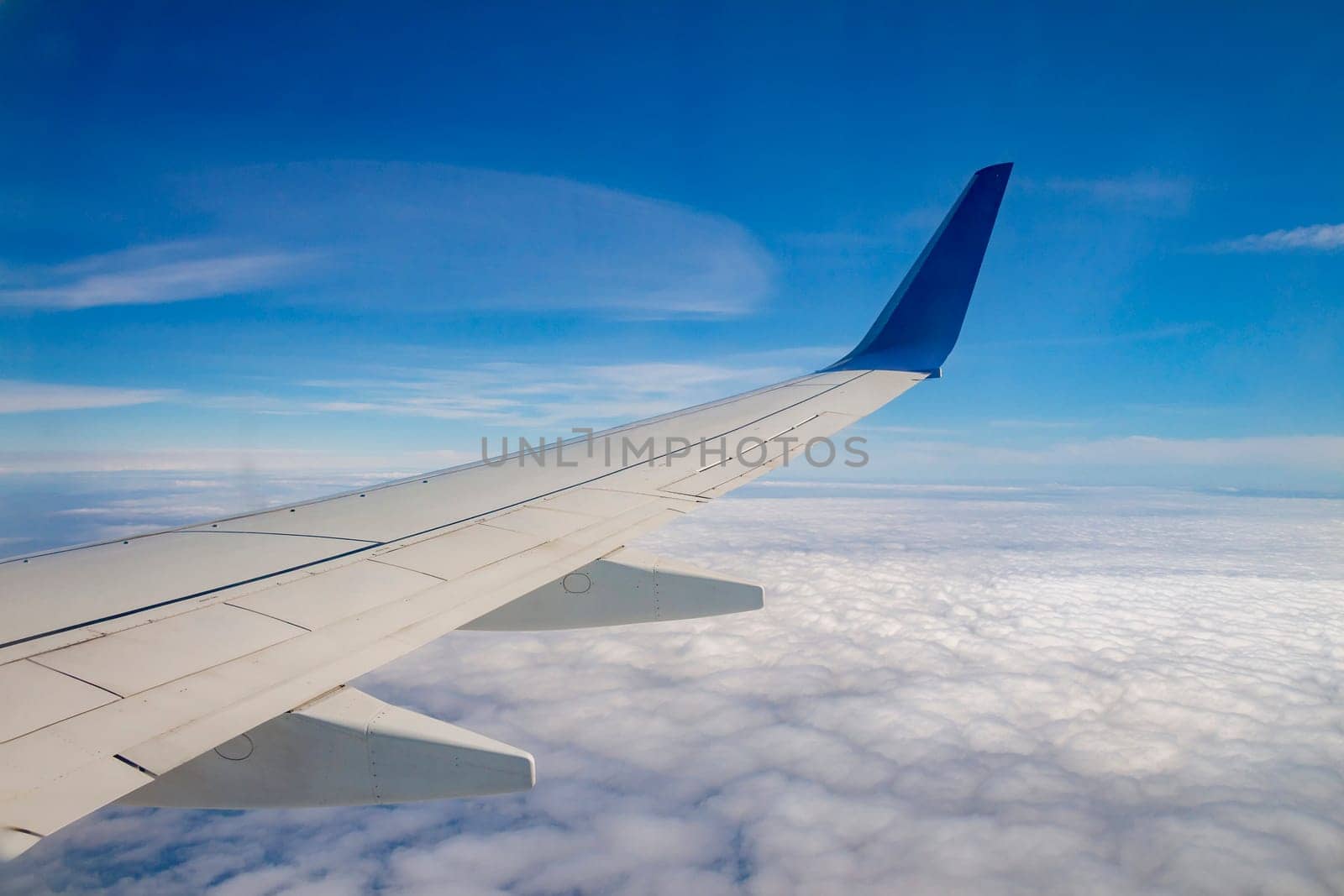 Airplane wing on the sky and over sea with clouds.