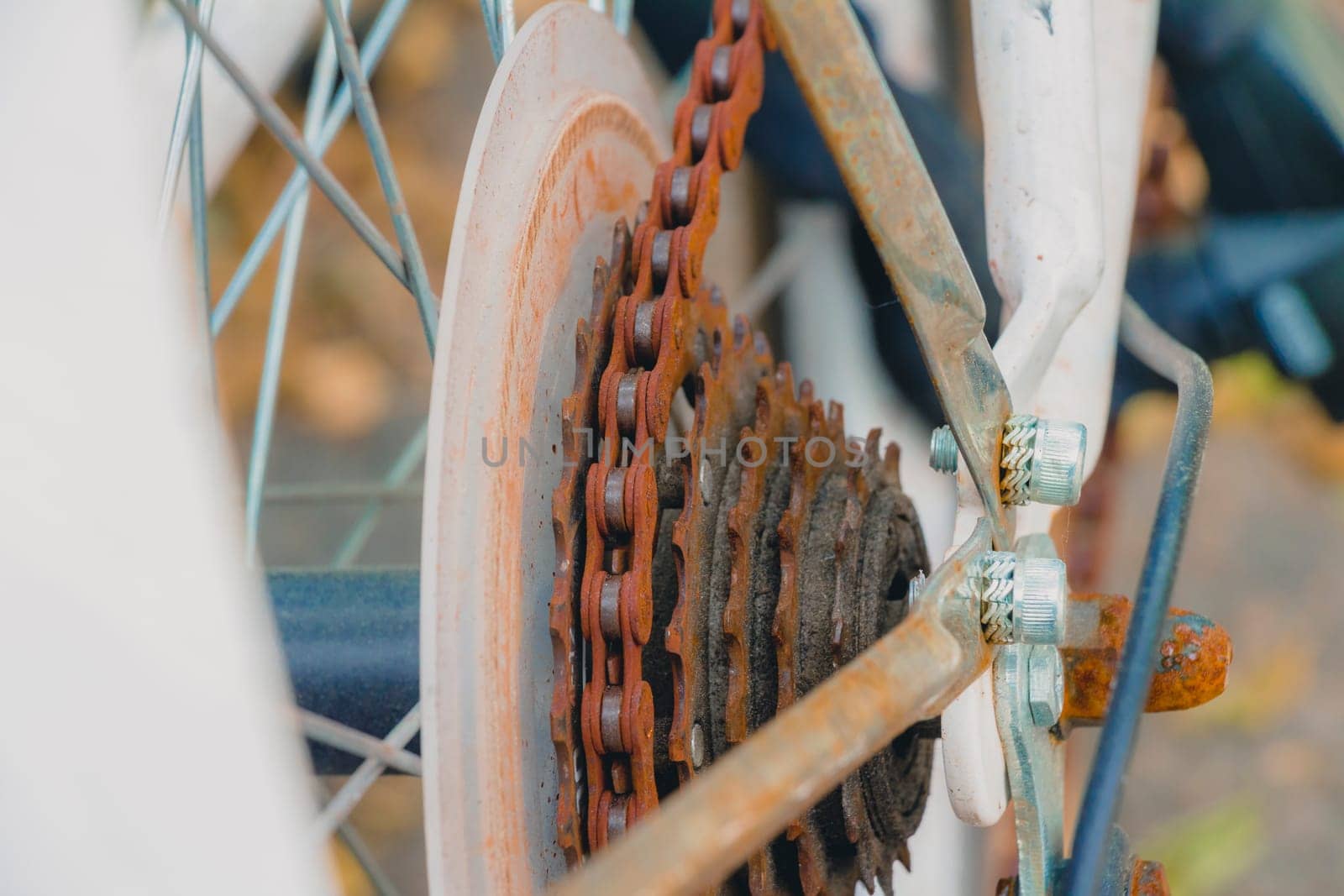 Old rusty chain on white bicycle. Selective focus close up.