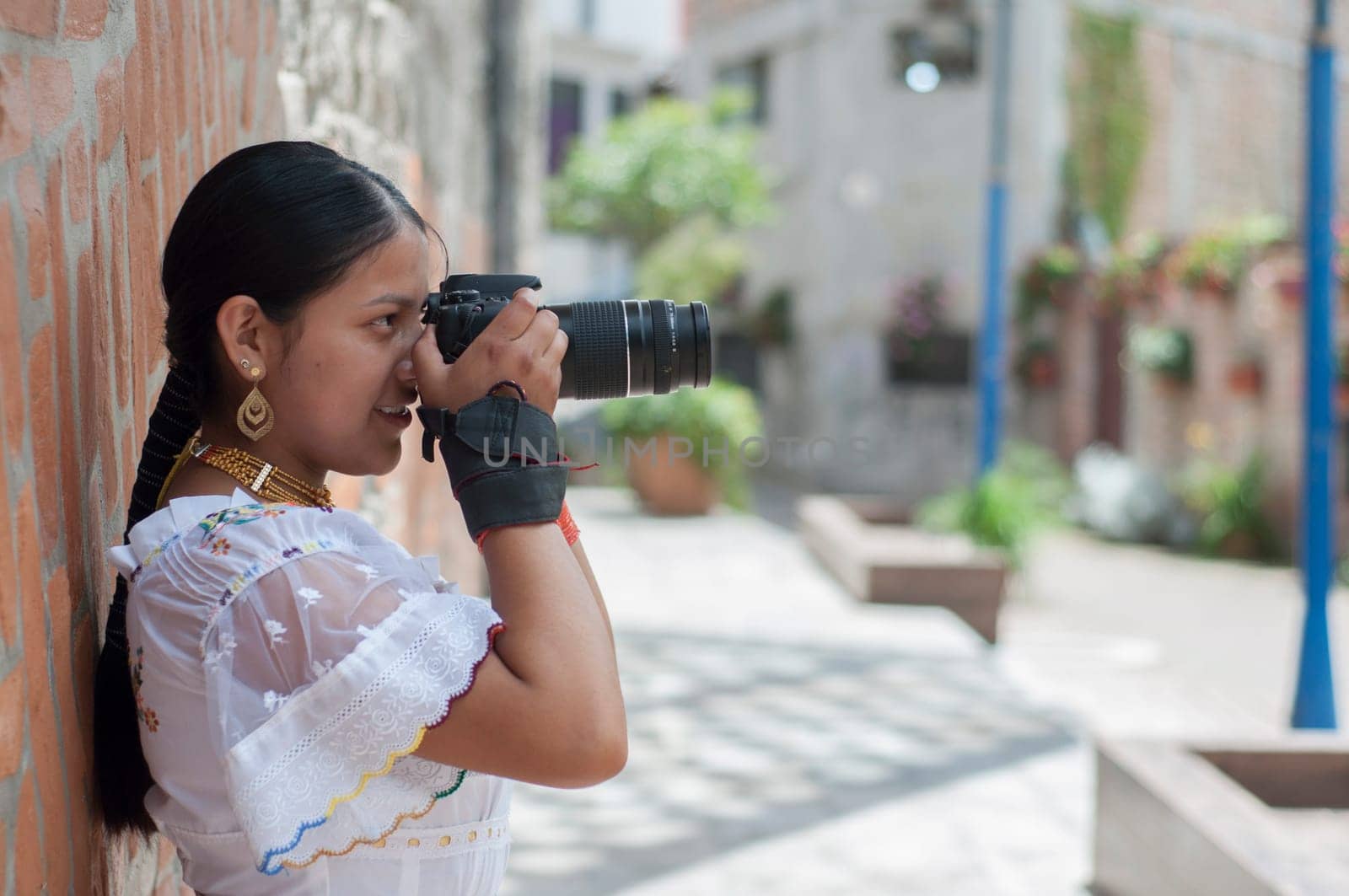 indigenous girl in traditional dress focuses reflex camera while sightseeing. High quality photo