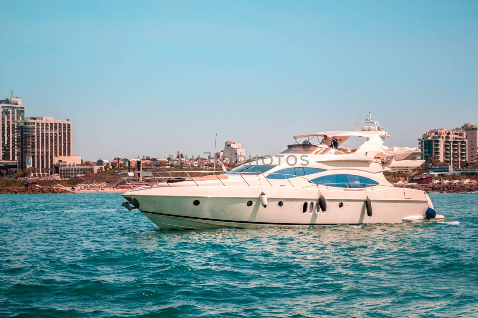 Yacht in the sea. Buildings in the background with blue sky.