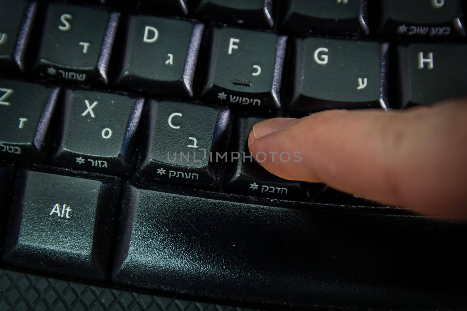 Man typing on a Wireless keyboard with letters in Hebrew and English - Press the Paste button - Top View - Dark atmosphere