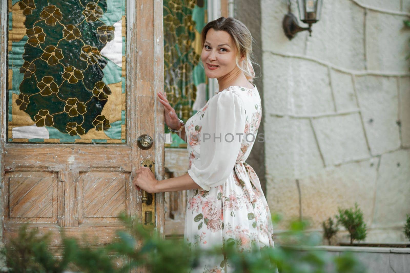 a woman in a flower dress opens the door to the house.