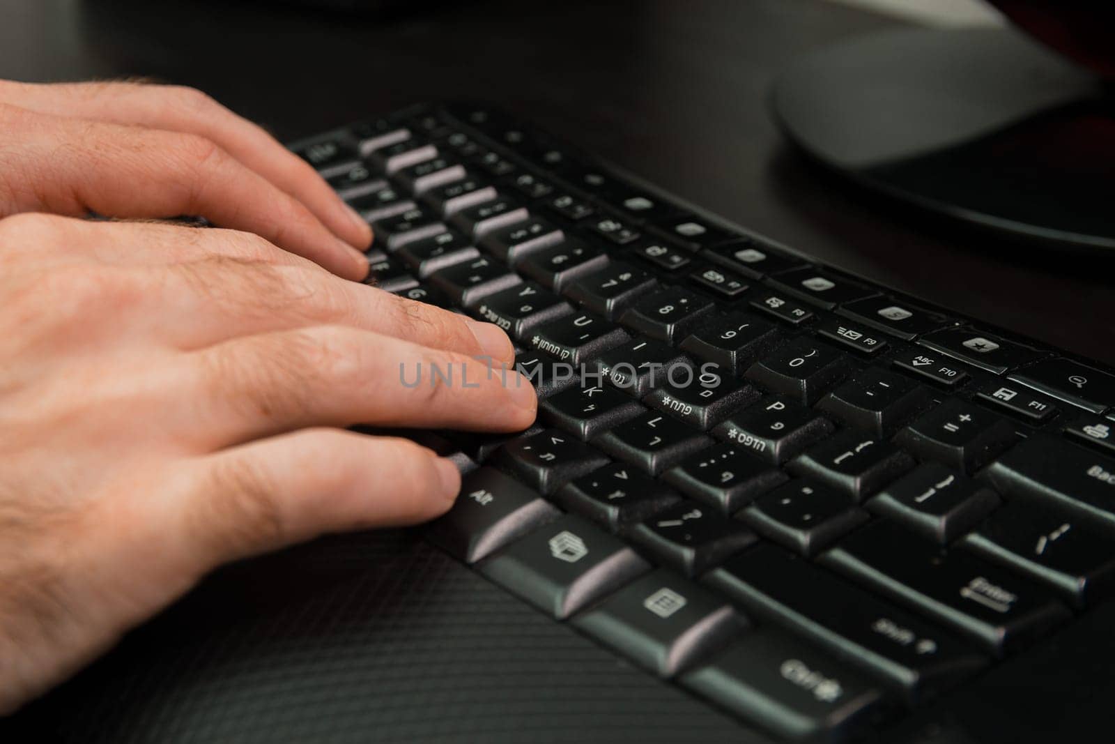 Man typing on a keyboard with letters in Hebrew and English - Wireless keyboard