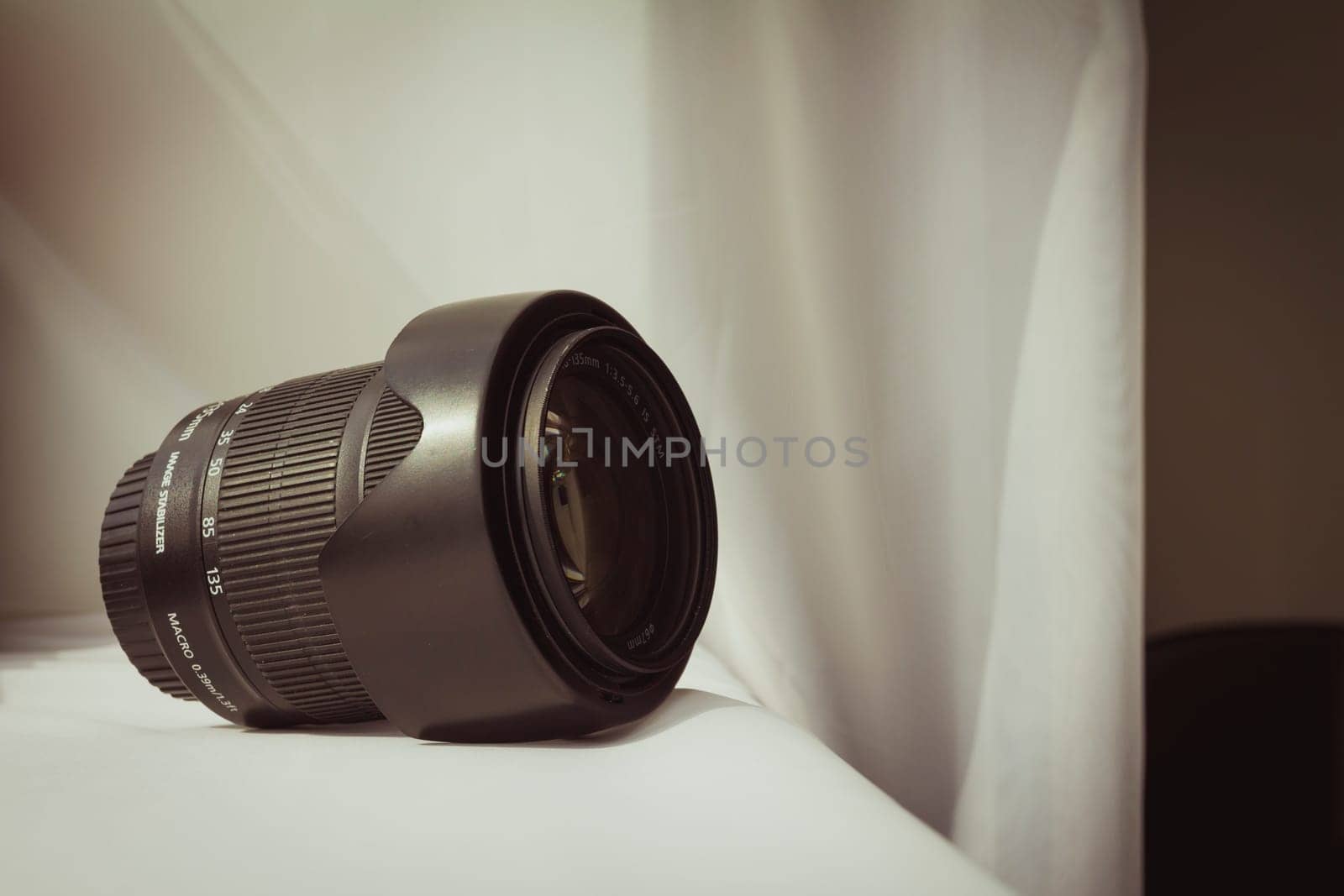 Black camera zoom lens on white cloth.