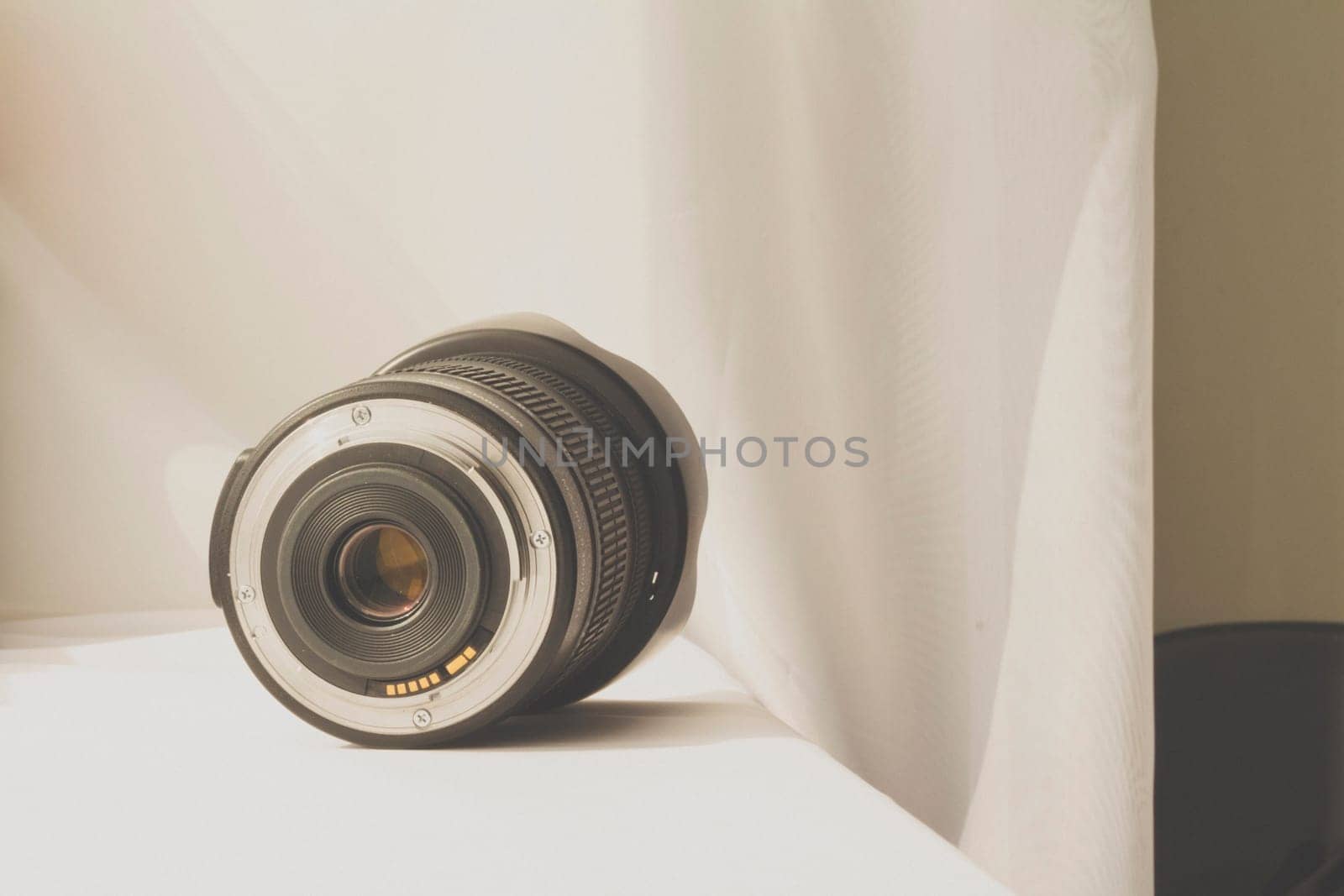 Black camera zoom lens on white cloth by wavemovies