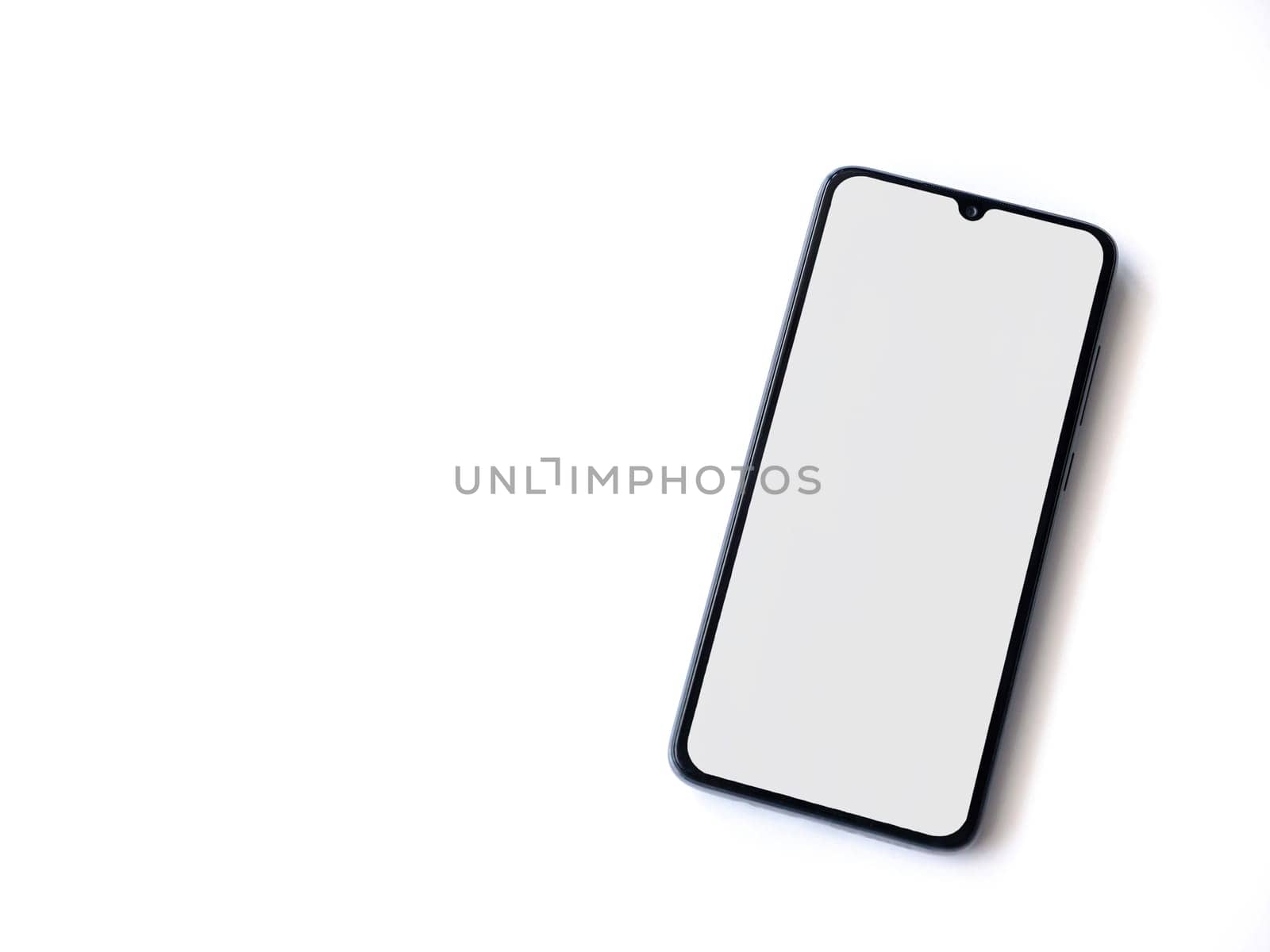 Black mobile smartphone mockup lies on the surface with blank screen isolated on white background. Top view flat lay with copy space.
