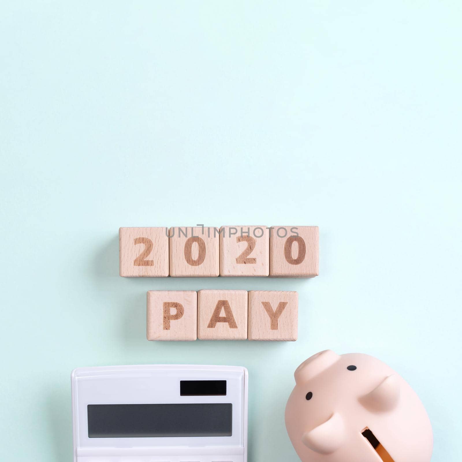 2020 goal, finance plan abstract design concept, wood blocks on green table background with piggy bank and calculator, top view, flat lay, copy space.