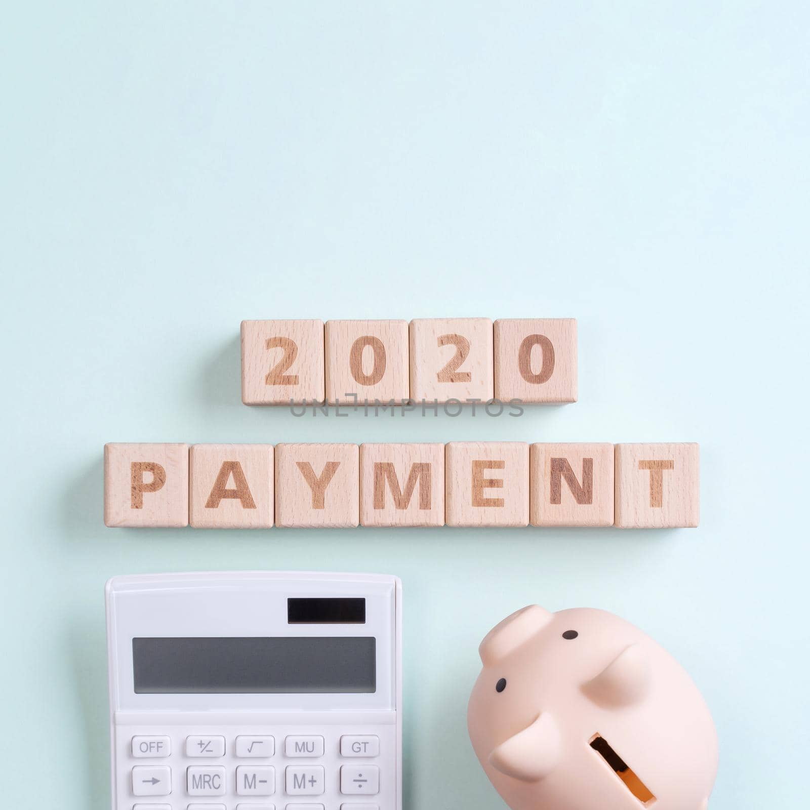 2020 goal, finance plan abstract design concept, wood blocks on green table background with piggy bank and calculator, top view, flat lay, copy space.