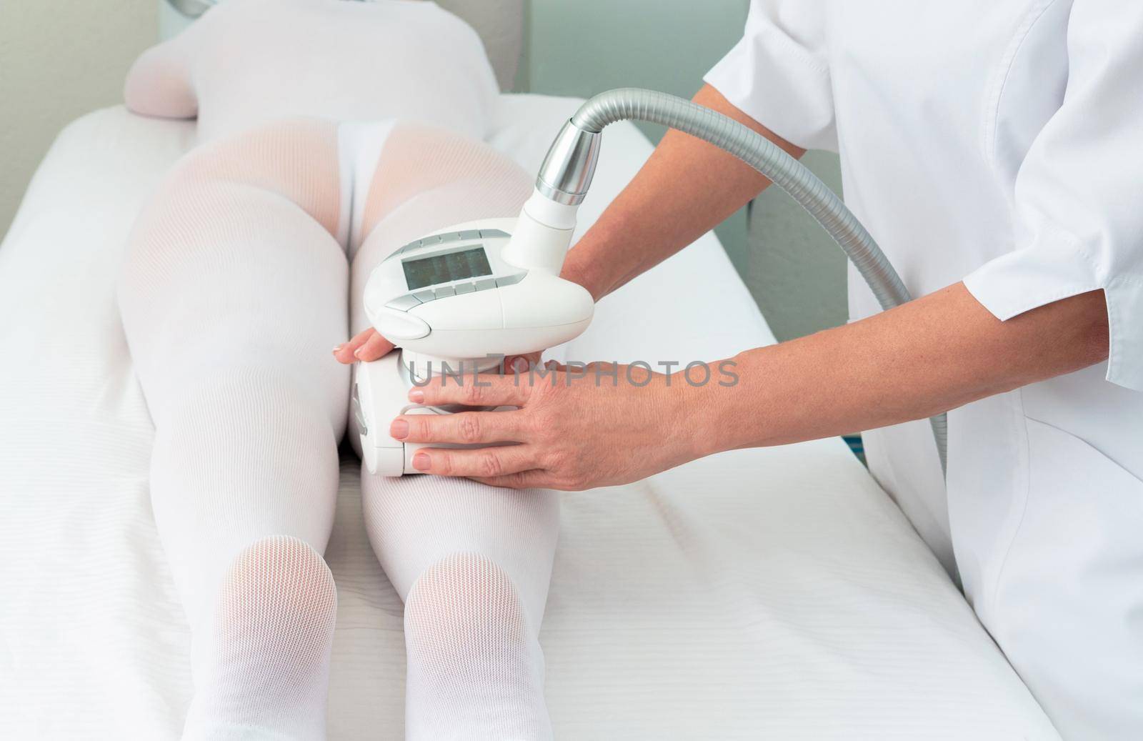 Woman in special white suit getting anti cellulite massage in a spa salon. LPG, and body contouring treatment in clinic