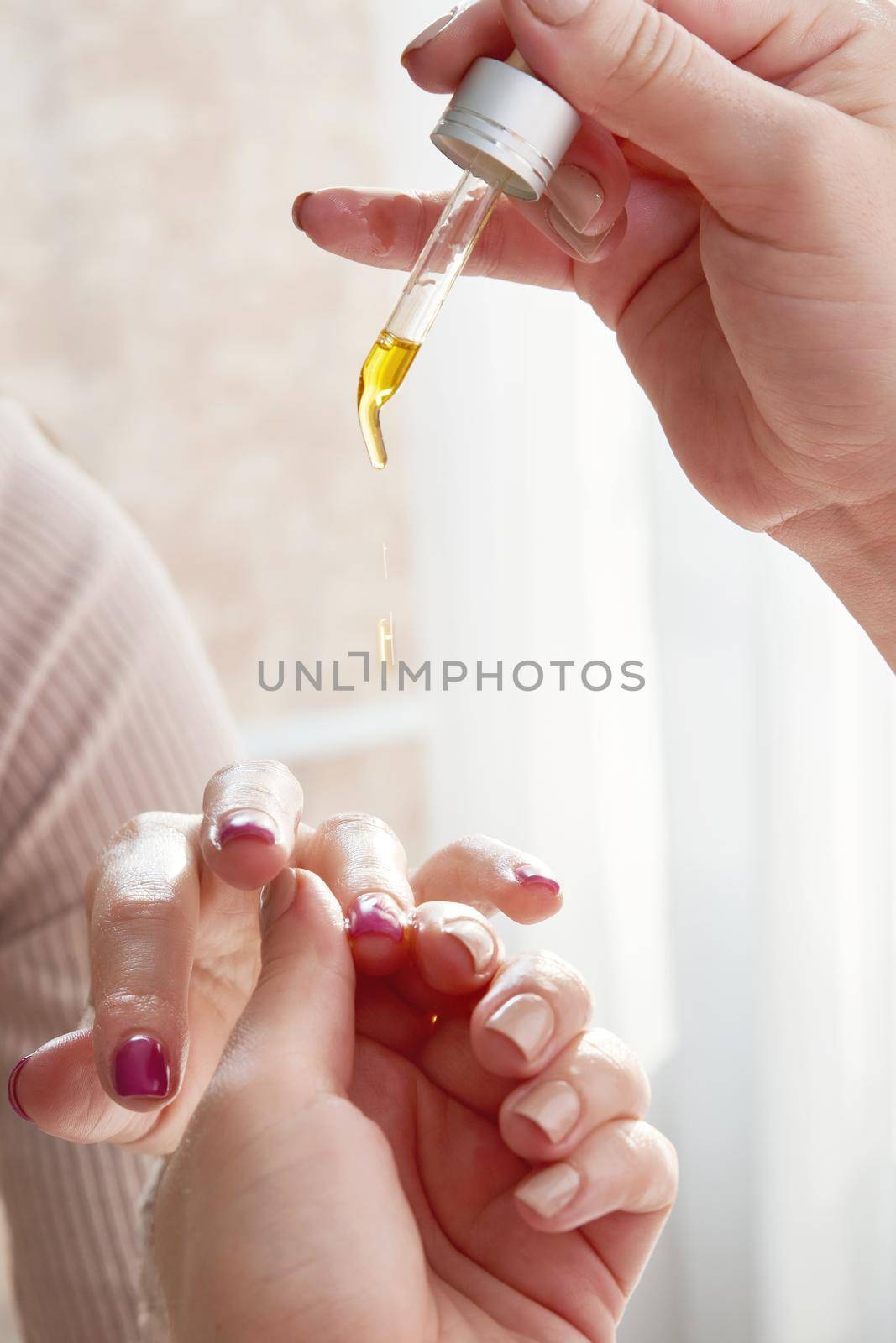 Cuticle care. Female hand applying oil on nails by Mariakray