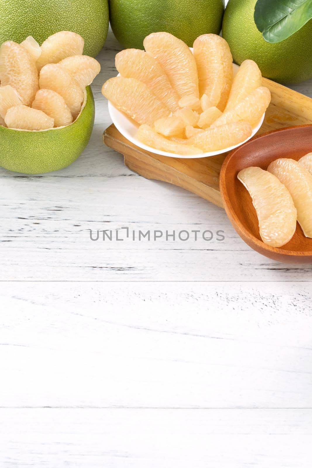 Fresh peeled pomelo, pummelo, grapefruit, shaddock on bright wooden table background. Seasonal fruit for Mid-Autumn Festival, close up, copy space.