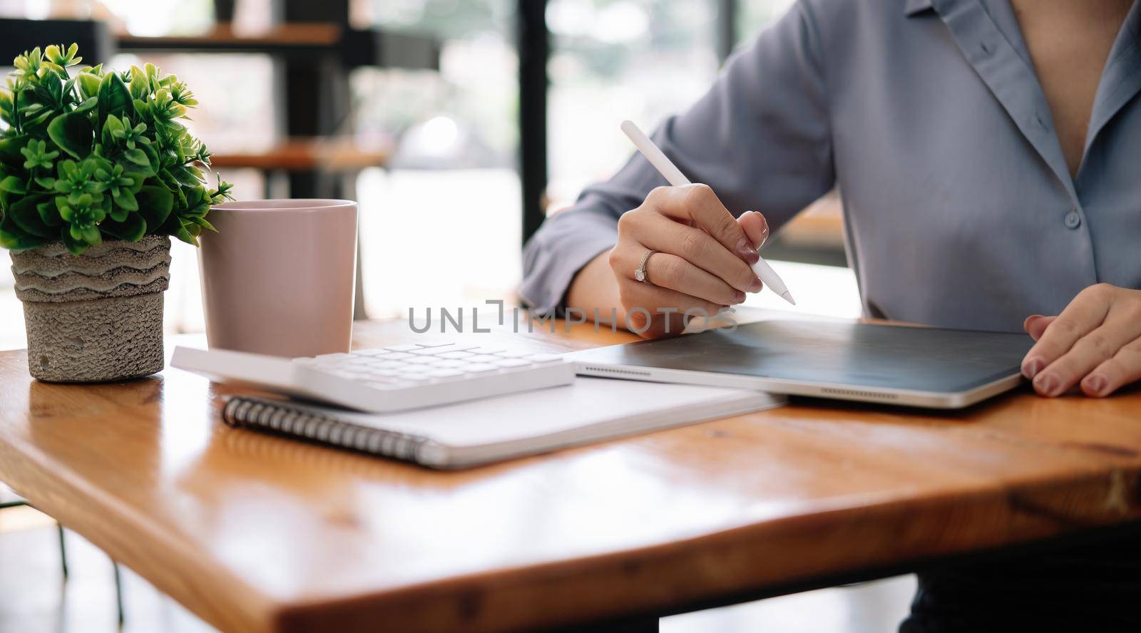 Close up business accountant using digital tablet for calculate finance on wooden desk.