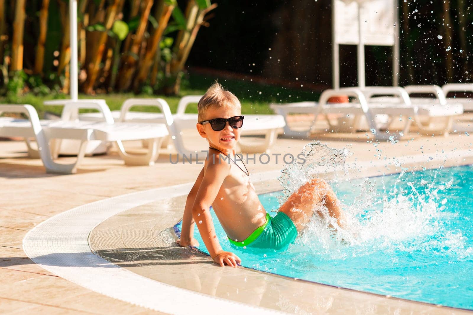 Happy little boy having fun at the pool at the resort. Summer holiday for kids concept