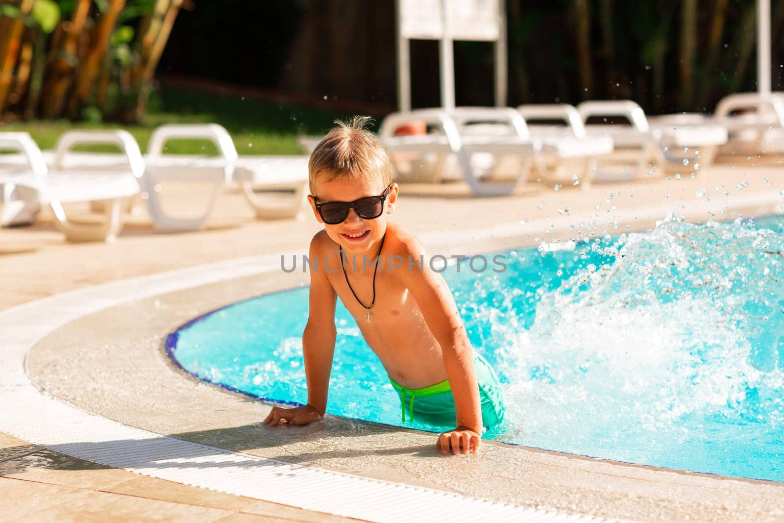 Happy little boy having fun at the pool at the resort. Summer holiday for kids concept