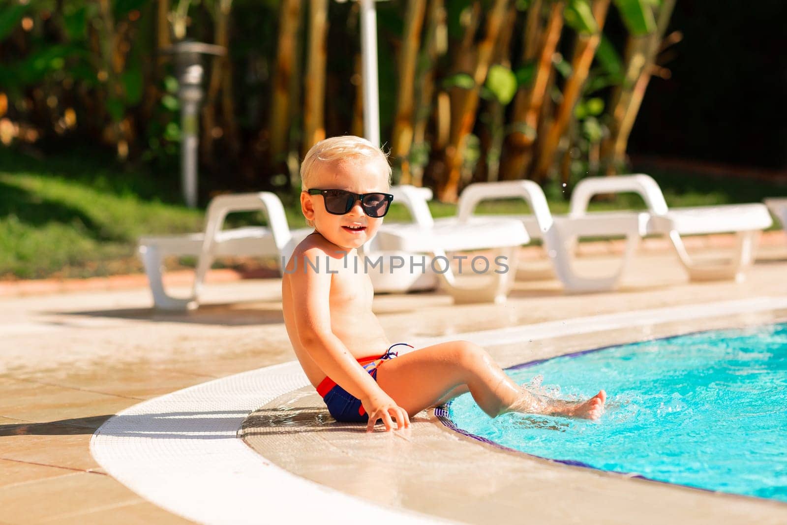 Happy little boy having fun at the pool at the resort. Summer holiday for kids concept