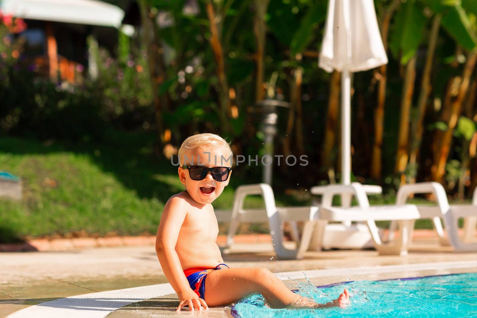 Happy little boy having fun at the pool at the resort. Summer holiday for kids concept