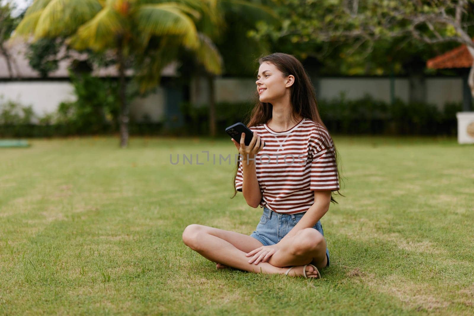 park woman student tree lifestyle grass blogger nature smiling happy palm phone by SHOTPRIME