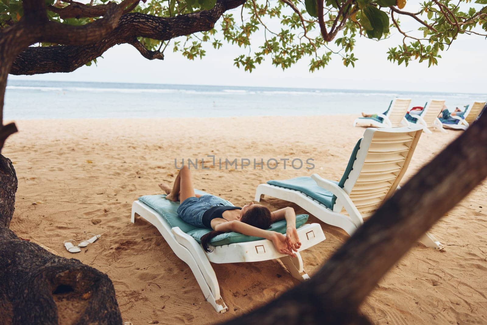 woman hat ocean lifestyle beach attractive sunbed lying relaxation beach young smiling relax chair sunglasses exotic resort brunette resting sand tan sea