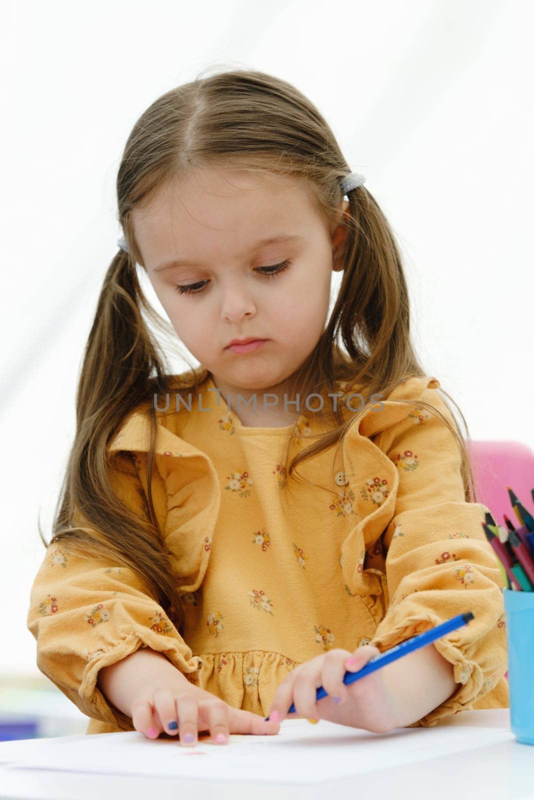 Portrait of a happy european kid girl painting with colored pencil. by leonik