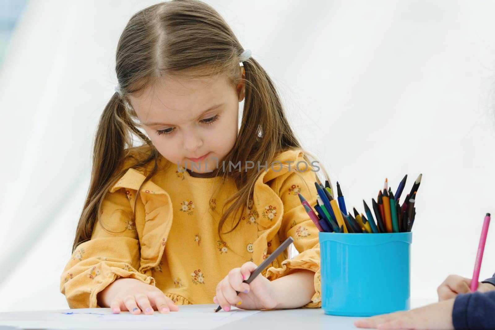 Cute european kid girl painting with colored pencil. Kindergarten children education concept. by leonik