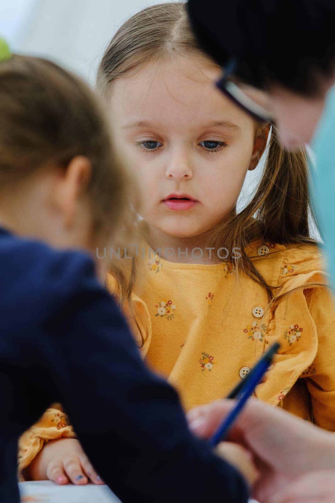 Cute european kid girl painting with colored pencil. Kindergarten children education concept.