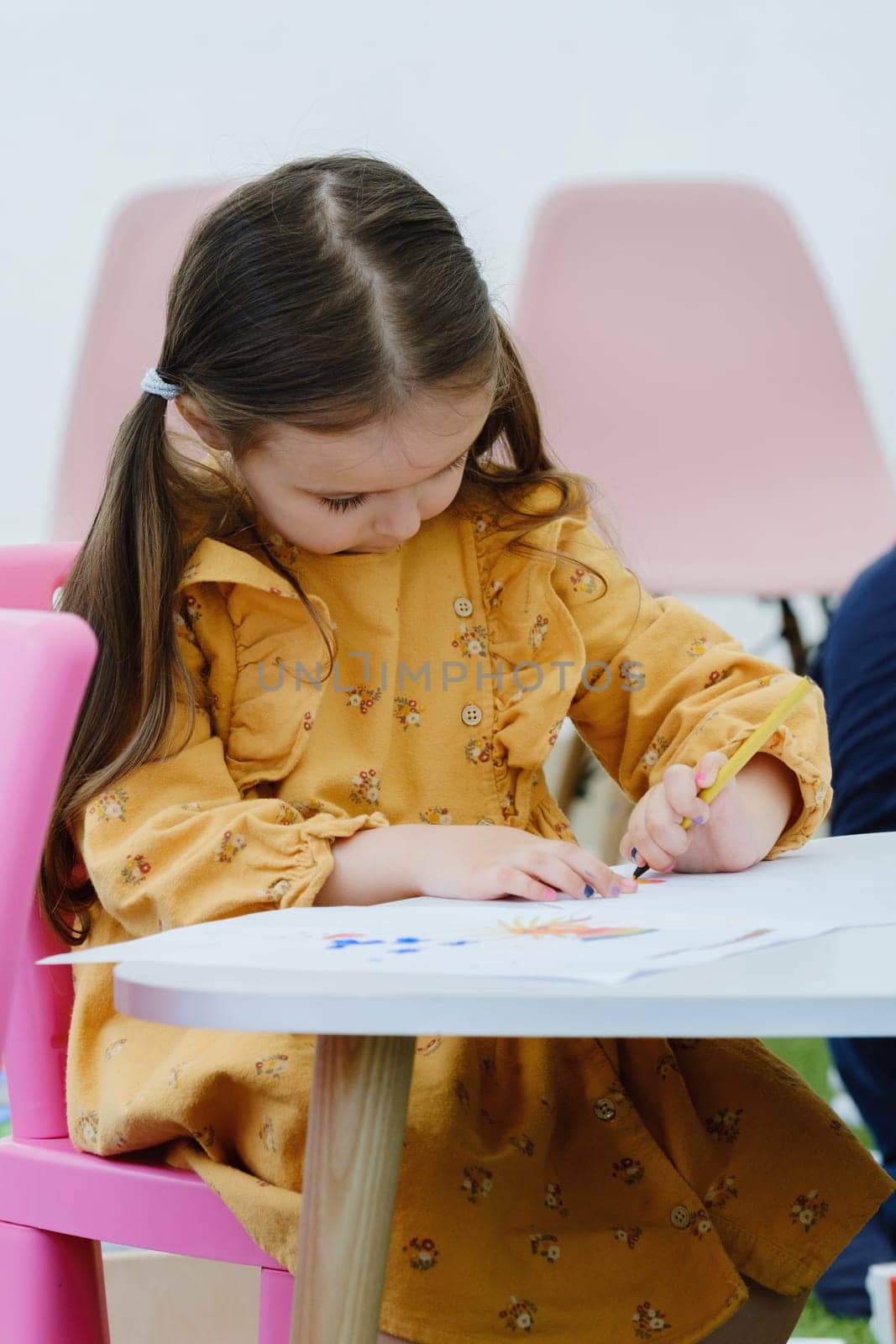 Cute european kid girl painting with colored pencil. Kindergarten children education concept.