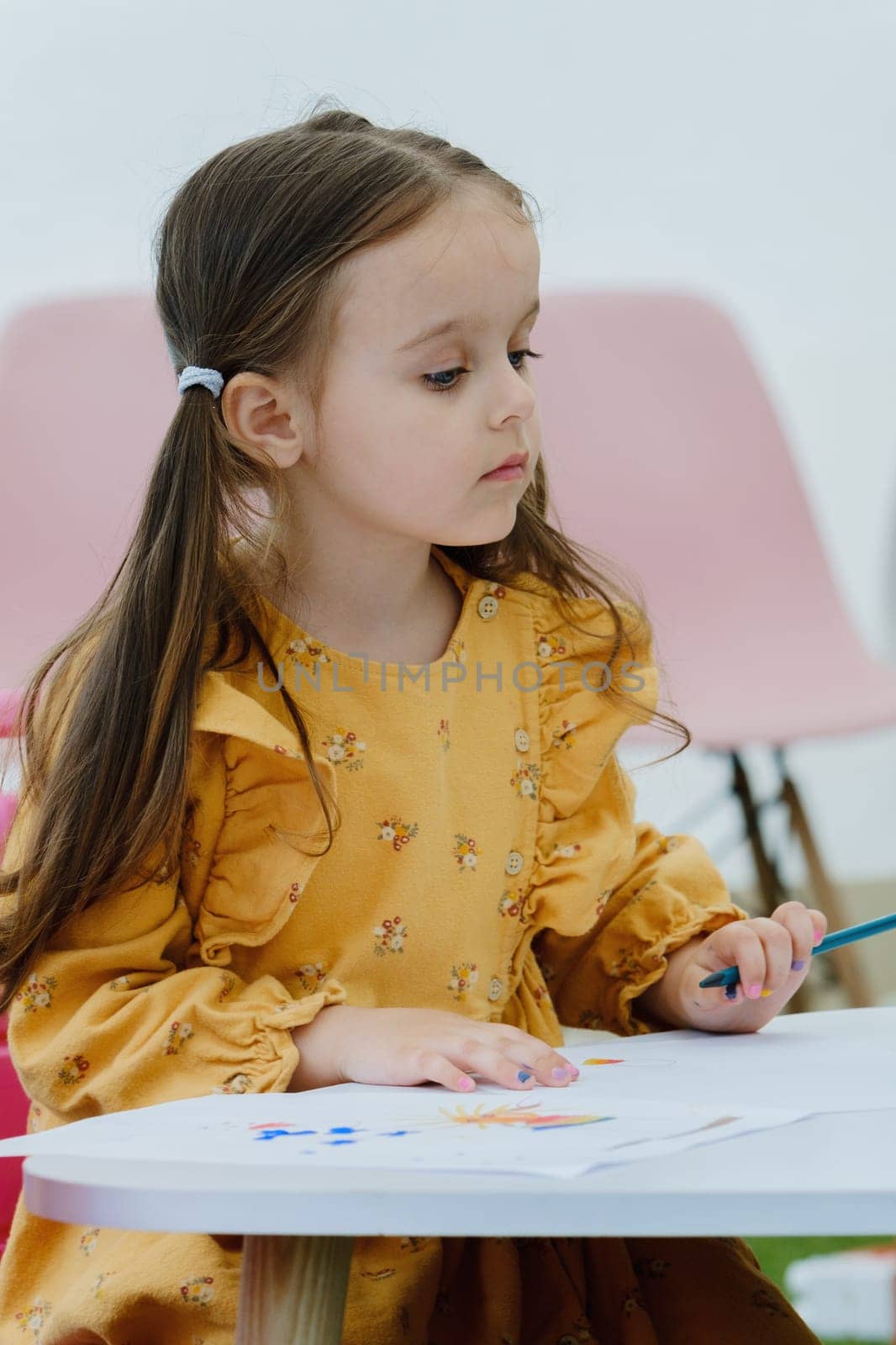 Girl painting with colored pencil. Kindergarten children education concept.