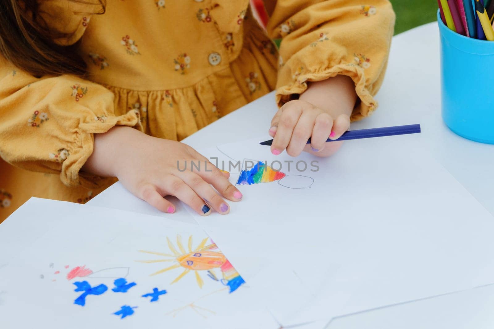 European kid girl painting with colored pencil. Kindergarten children education concept. Close-up of children's drawing.