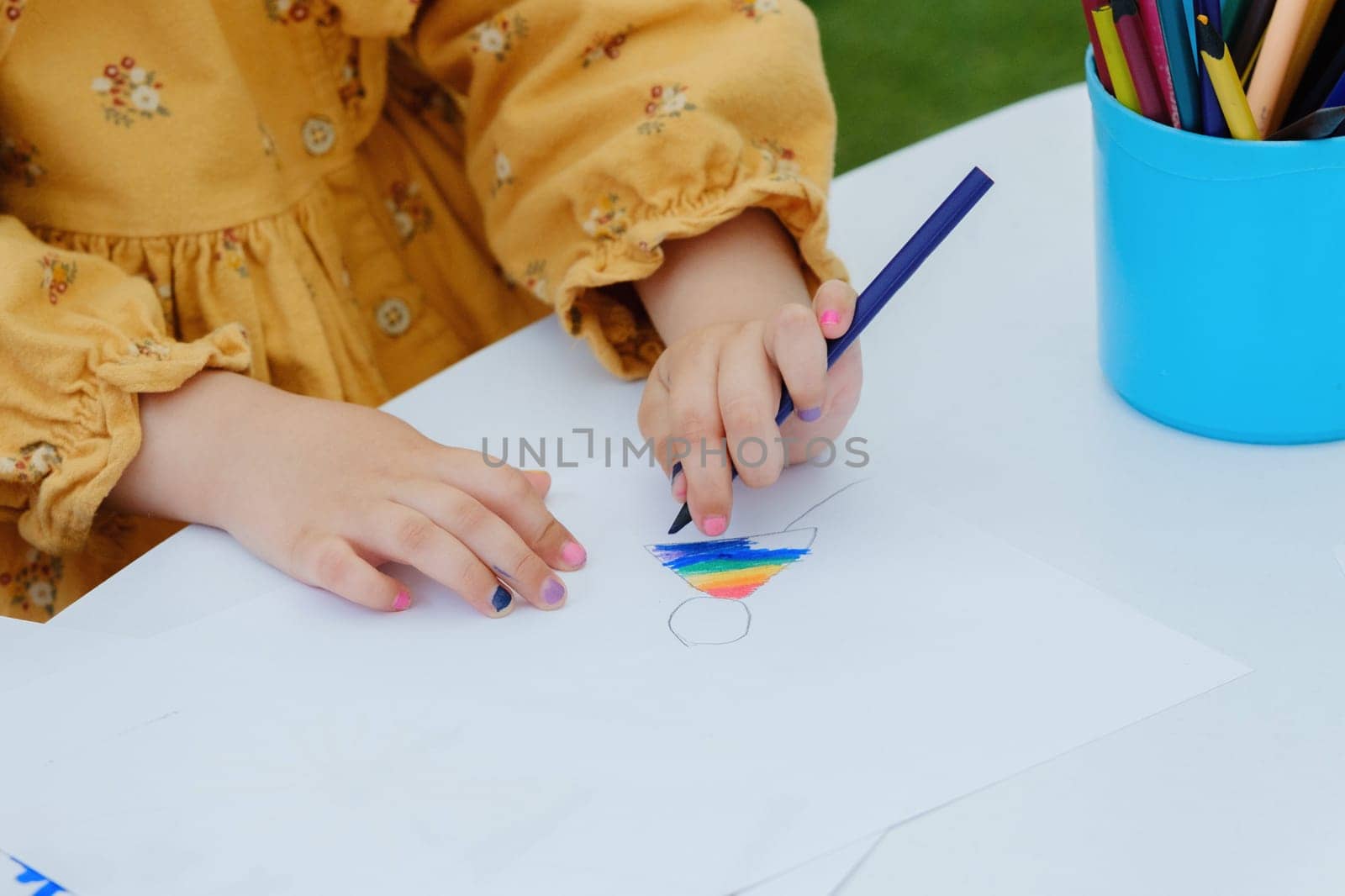 European kid girl painting with colored pencil. Kindergarten children education concept. Close-up of children's drawing.