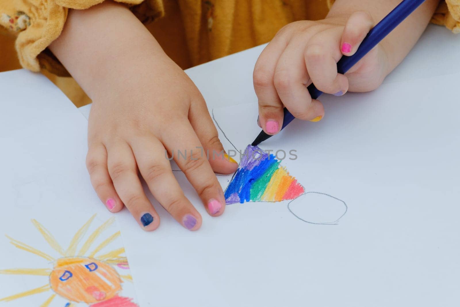 Girl painting with colored pencil. Kindergarten children education concept. Close-up of children's drawing.