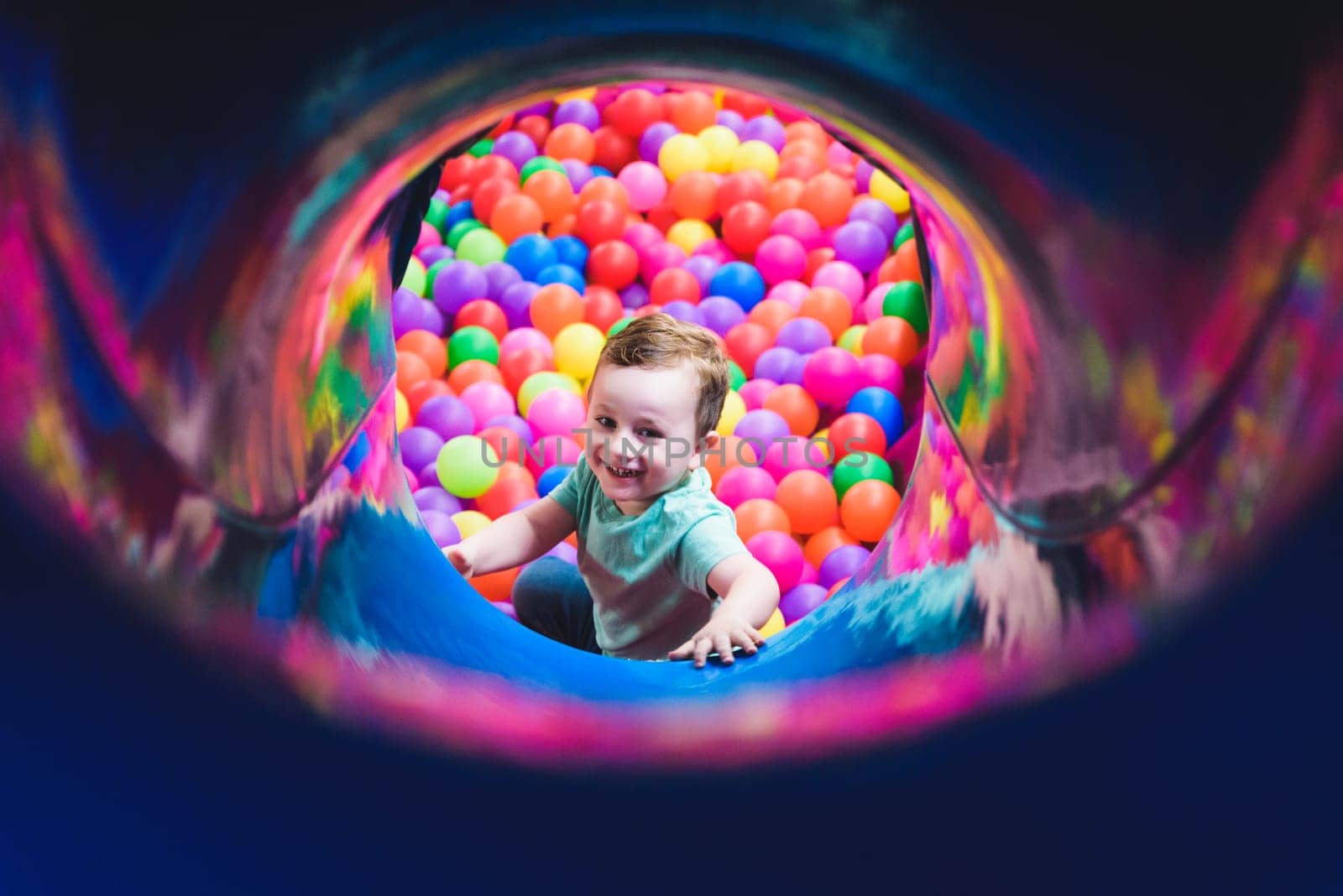 Child on the playground with colored plastic balls by jcdiazhidalgo