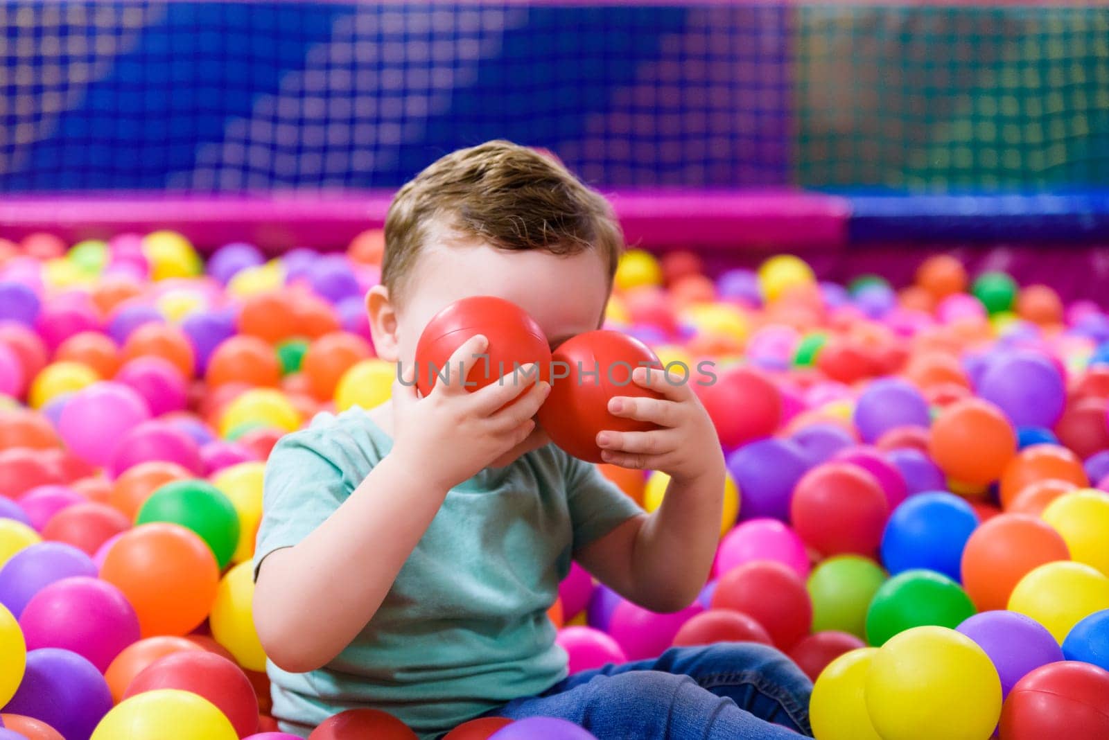 Happy laughing child laughing in an indoor play center. Children playing with colored balls in the playground ball pool. Party by jcdiazhidalgo
