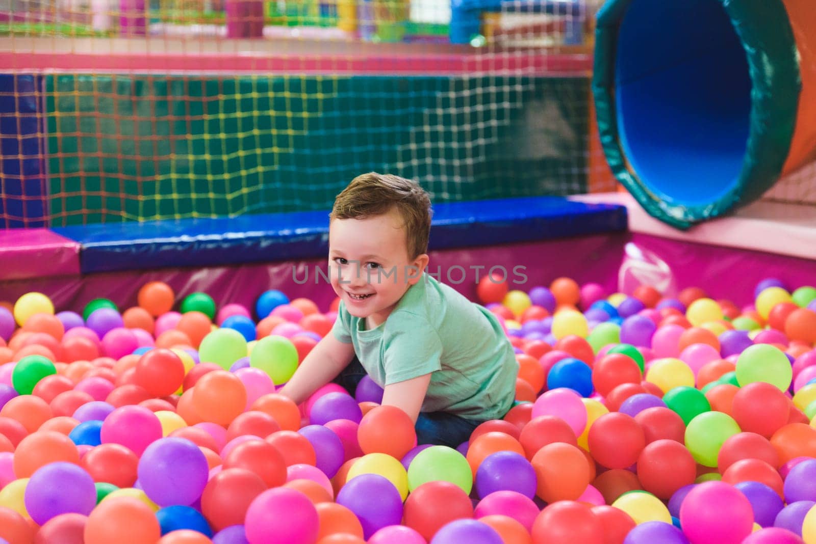 Happy laughing child laughing in an indoor play center. Children playing with colored balls in the playground ball pool. Party by jcdiazhidalgo