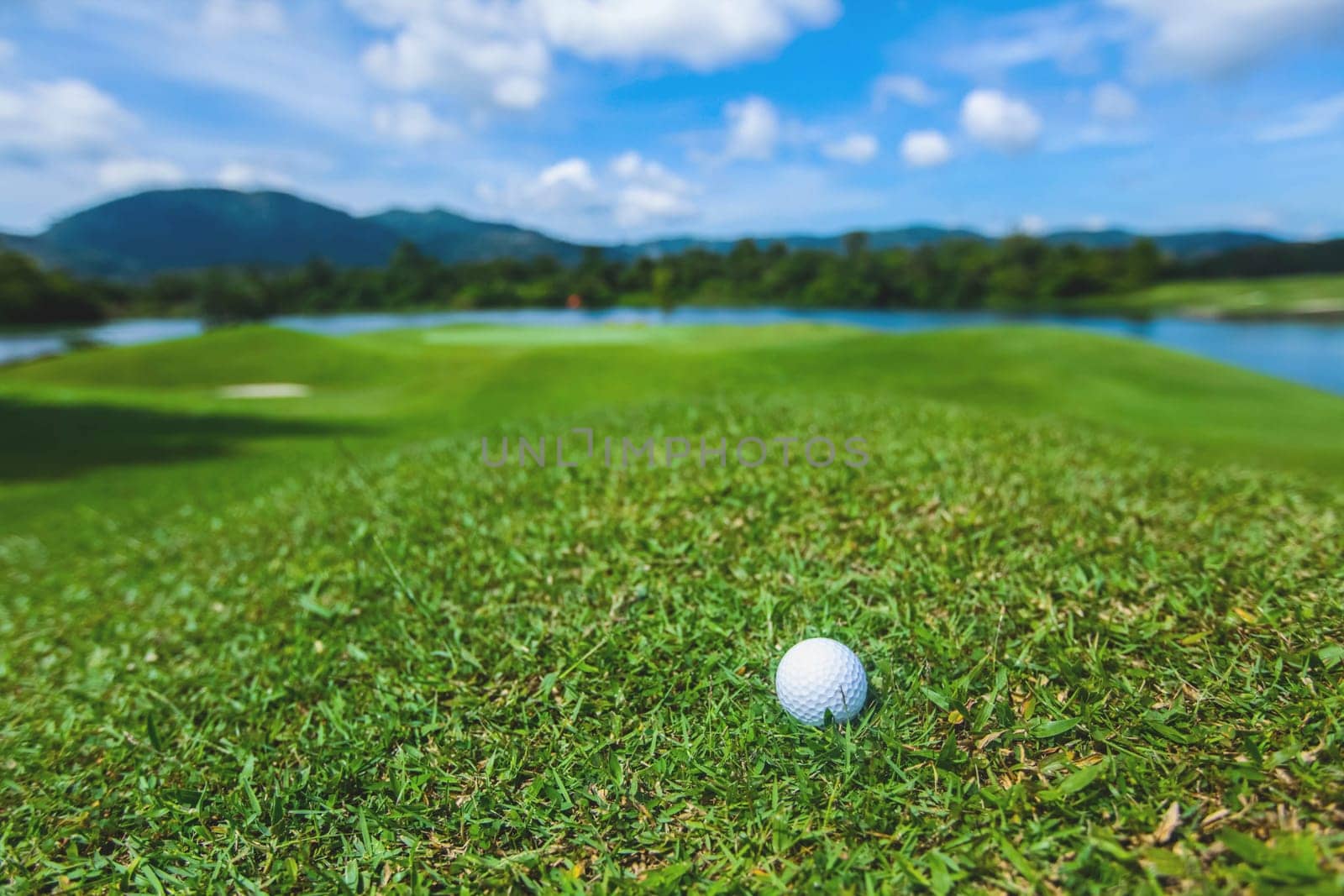 Golf ball on course, beautiful landscape with mountains on background