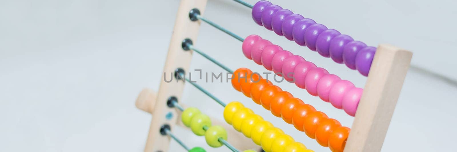 Preschooler baby learns to count. Cute child playing with abacus toy. Little boy having fun indoors at home, kindergarten or day care centre. Educational concept for preschool kids.