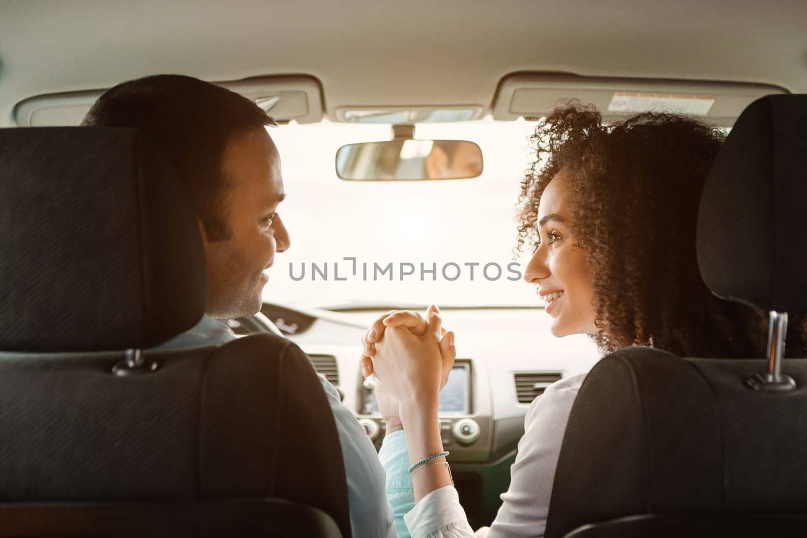 Road Trip. Rear View Of Young Arabic Couple In Car Holding Hands Enjoying First Ride In New Auto, Sitting On Front Driver And Passenger Seats Inside. Joy Of Vehicle Ownership And Family Journey