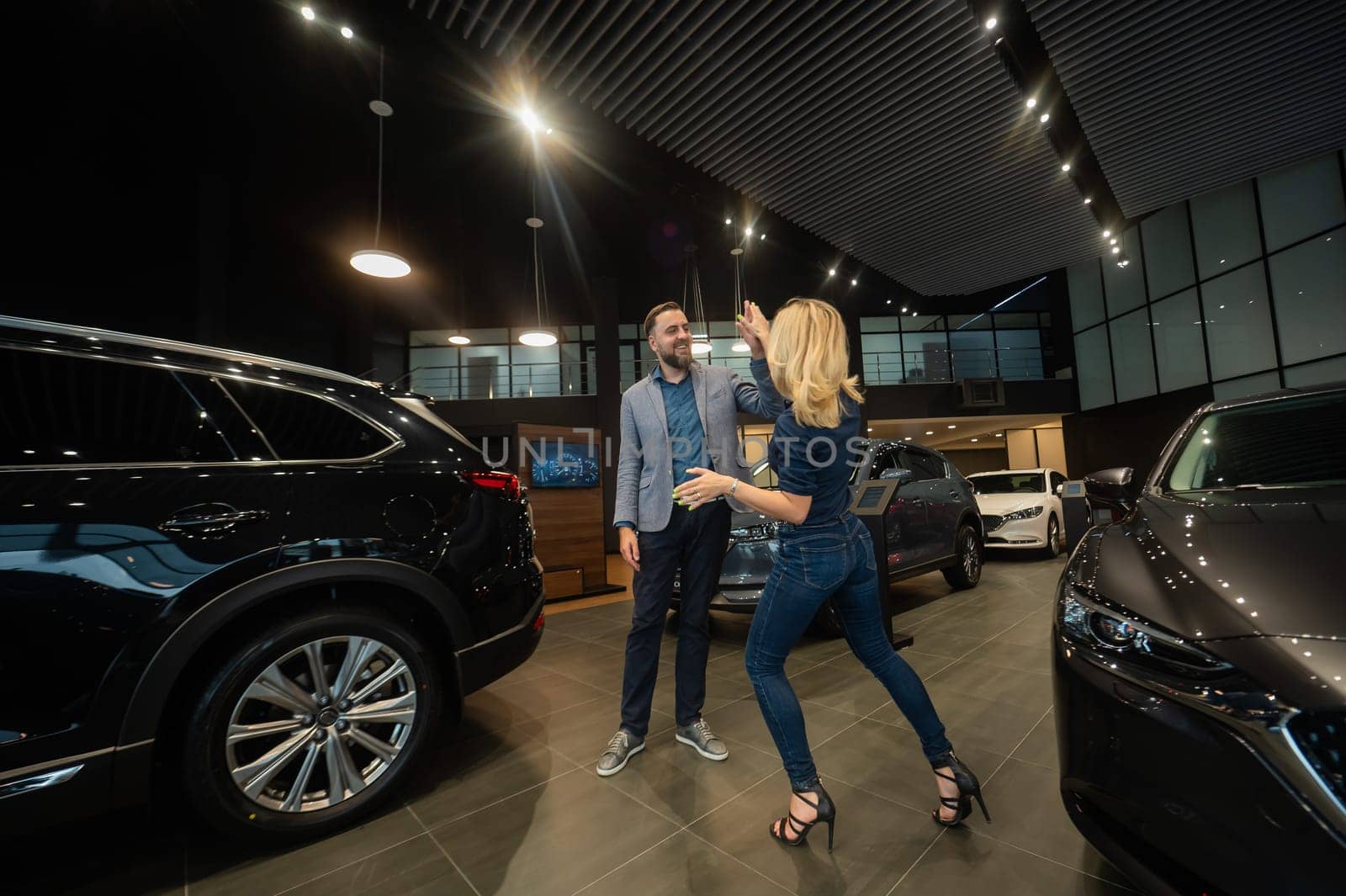 Happy married couple celebrating buying a car in a car showroom. by mrwed54