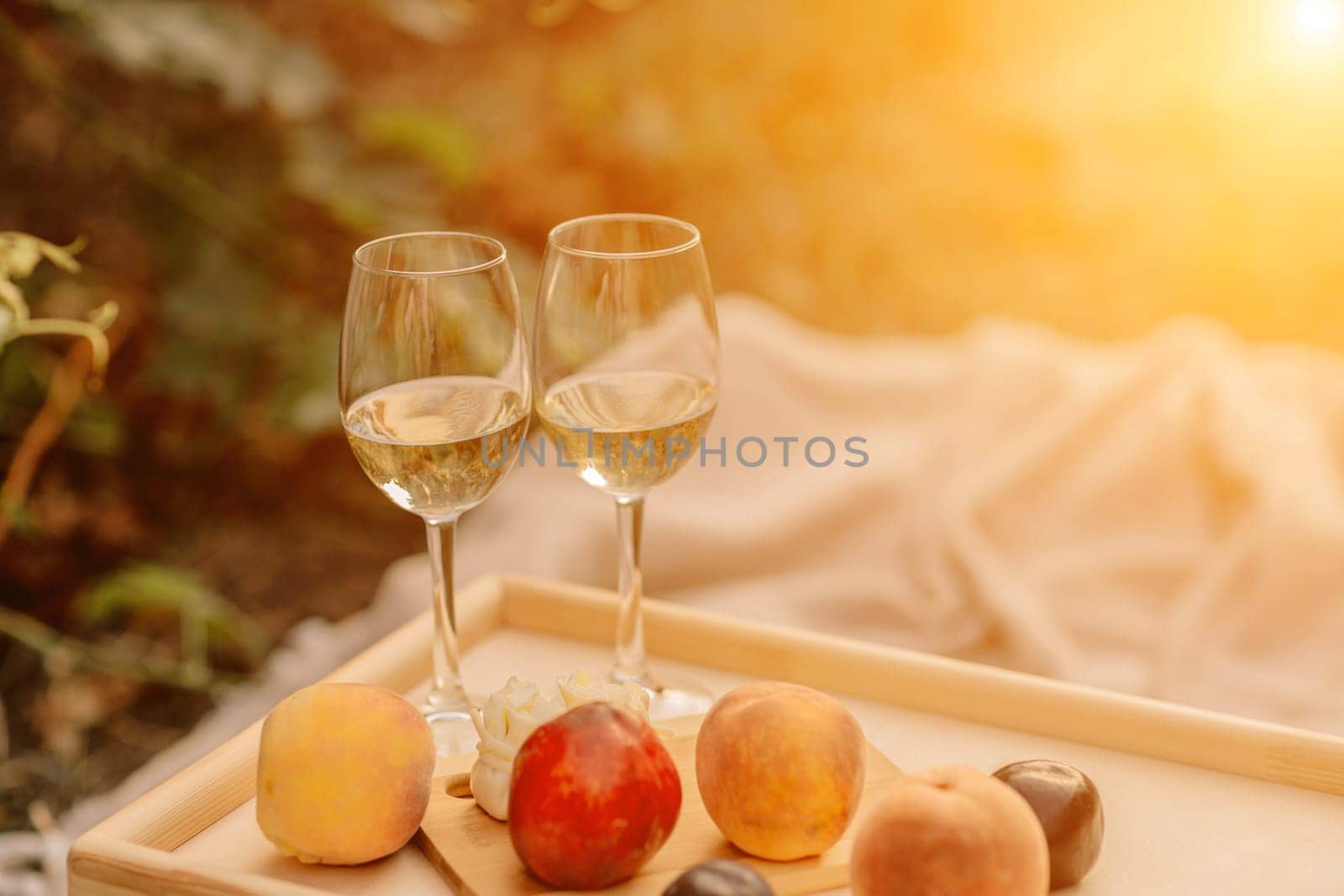 Glasses of a vineyard picnic. two glasses of white wine on a table overlooking the vineyards at sunset.