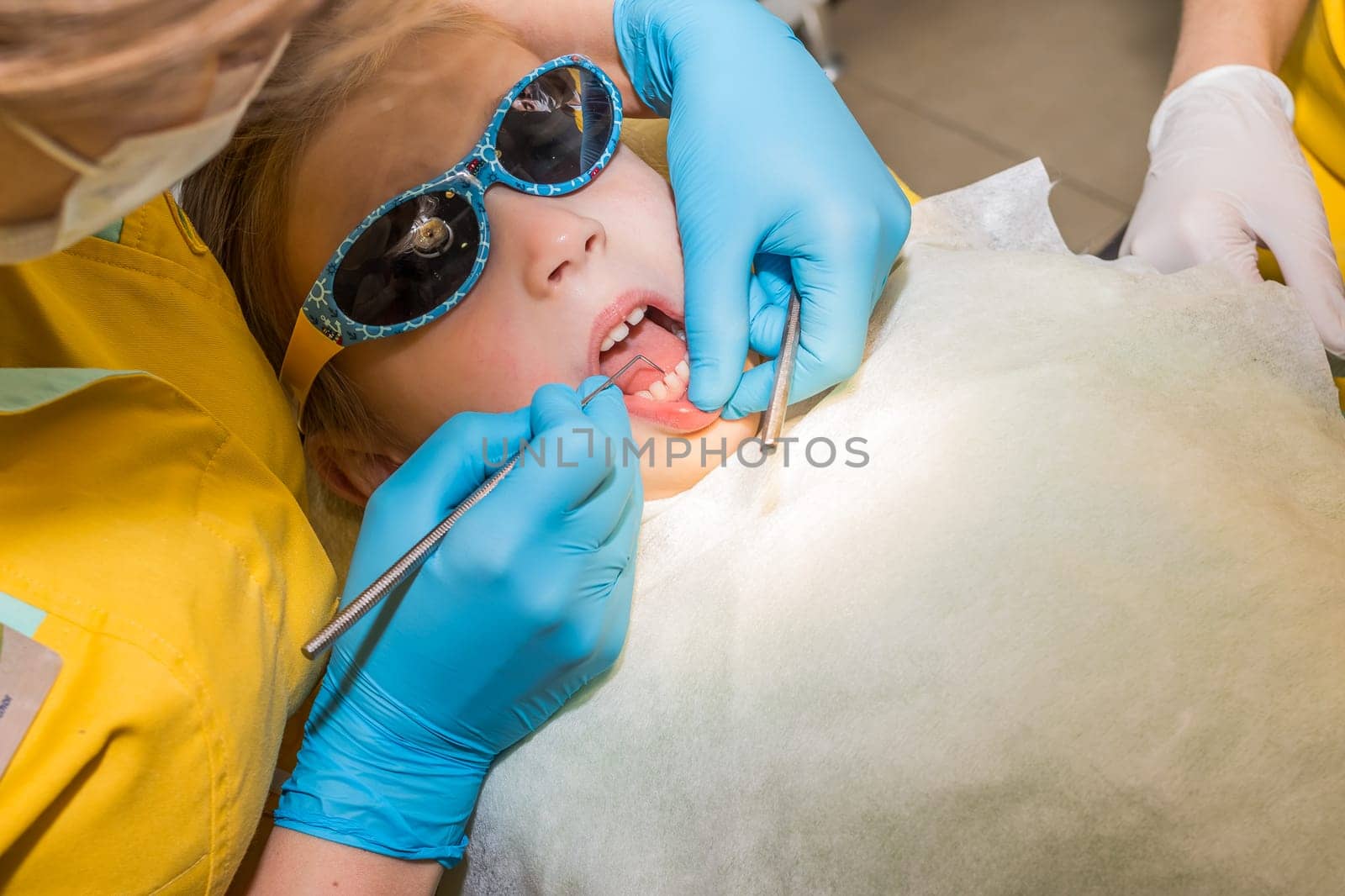Close up in child mount and checking tooth and by dental mirror tools. Dentist checked and curing teeth a child patient in the dental office by YuliaYaspe1979