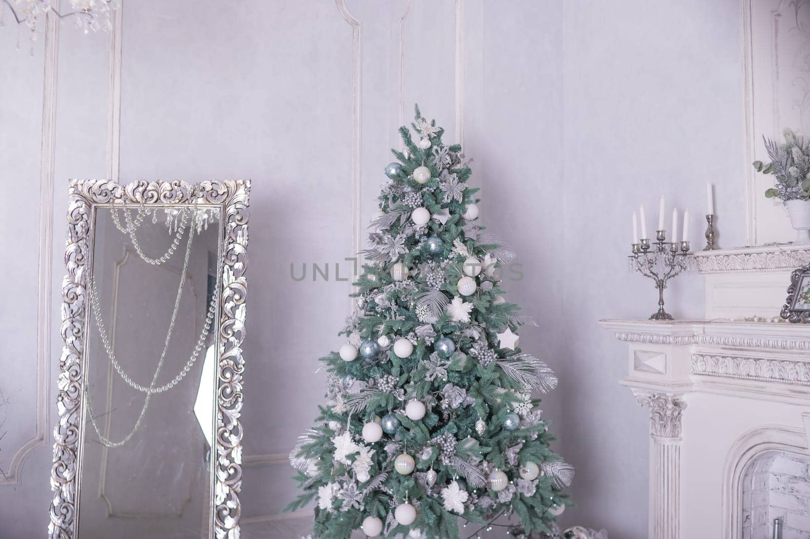 Christmas holiday background. Christmas tree with silver and white decoration. Beautiful Christmas tree closeup decorated with ball, holly berry, tinsel, pastel colors.